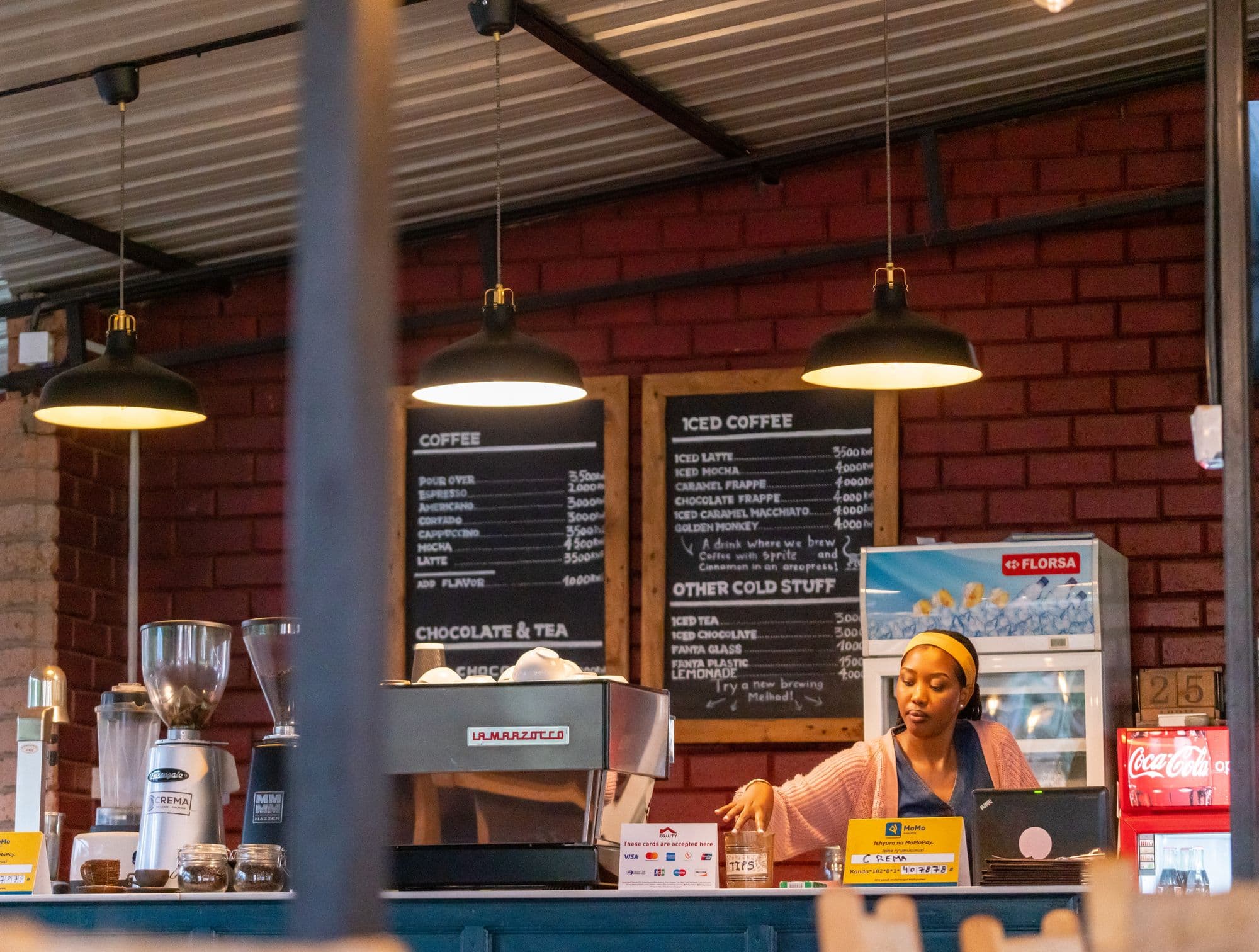 A café counter with a till, espresso machine and handwritten menu boards