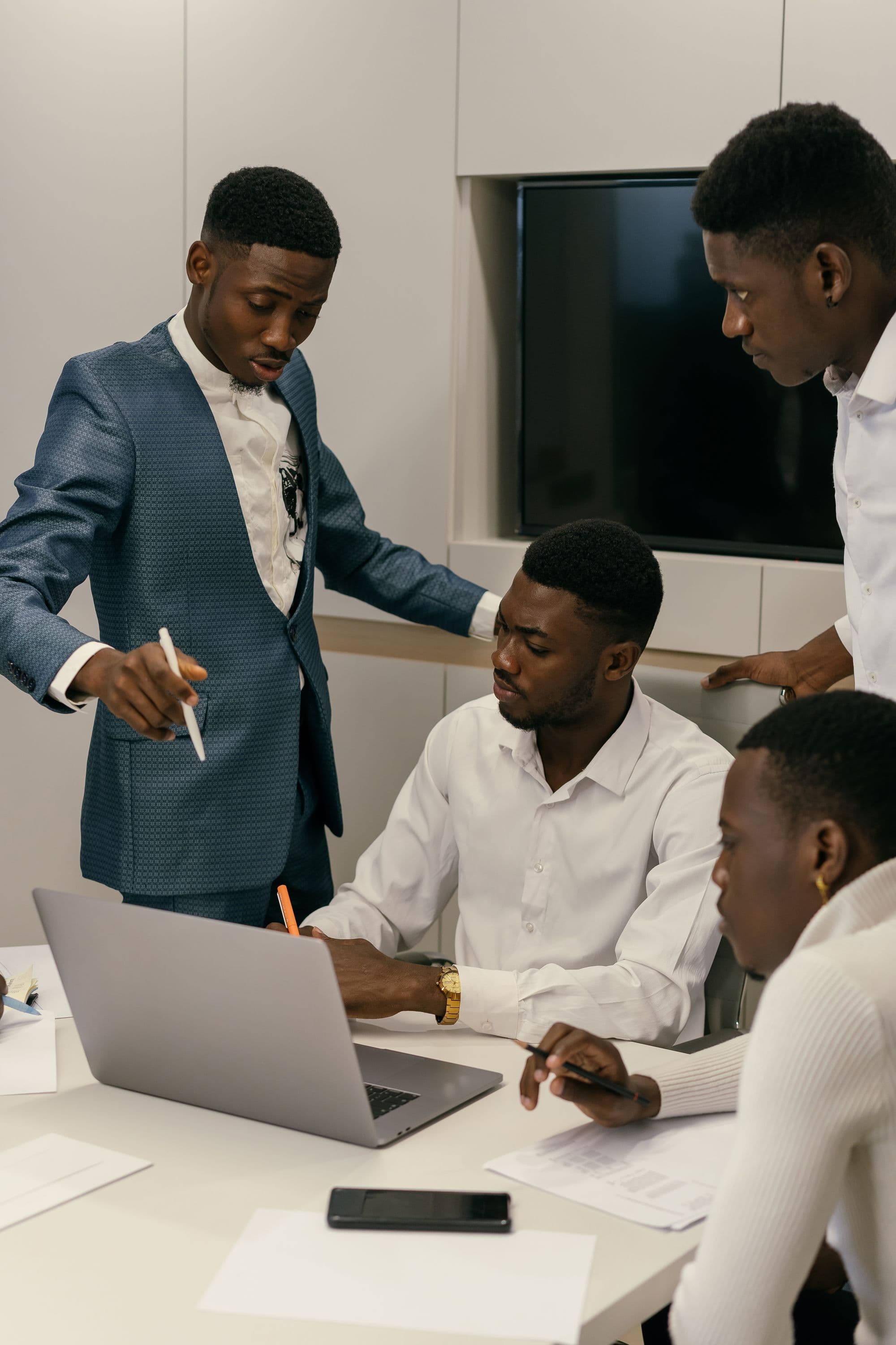 A small team in discussion around a laptop at a meeting table
